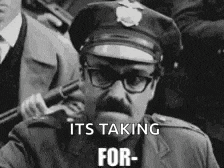 a black and white photo of a police officer holding a shotgun with the caption it 's taking for