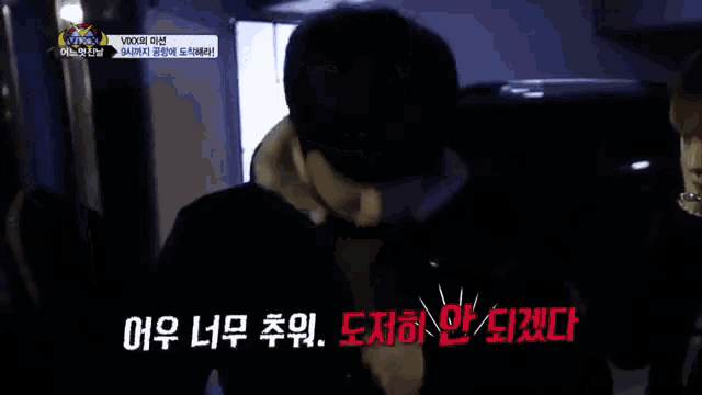 a man in a black jacket is standing in front of a sign that says ' vixx ' on it