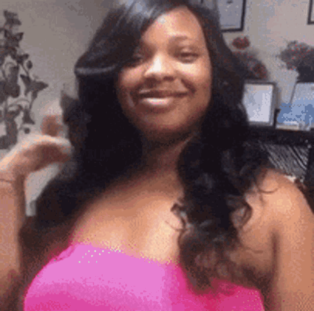 a woman is wearing a pink top and smiling