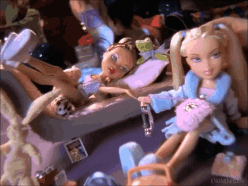 two dolls are laying on a bed and one is holding a bottle of water