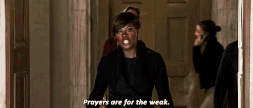a woman in a black jacket is standing in a hallway and says `` prayers are for the weak '' .