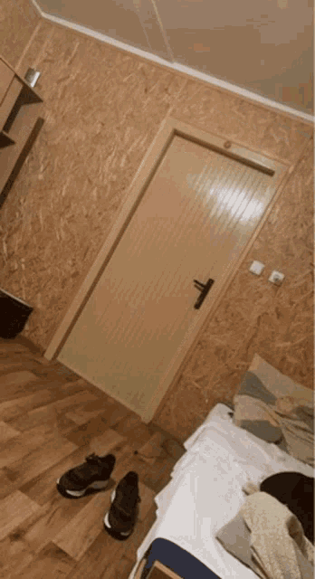 a bedroom with a door and a bed with a pair of sneakers on the floor