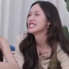 a woman with long black hair is making a funny face while sitting on a couch .
