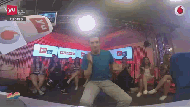 a man in a blue shirt is dancing in front of a group of people who are watching a tv show called yu