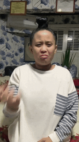 a woman wearing a white sweater with striped sleeves making a funny face