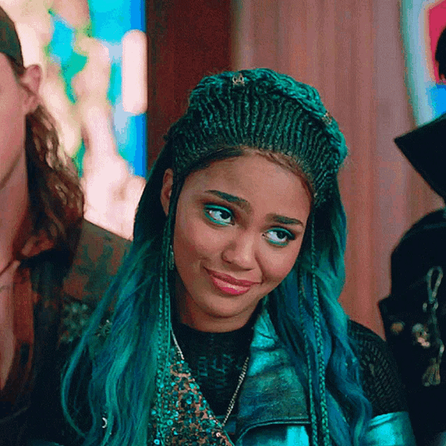 a woman with blue hair and braids looks at the camera