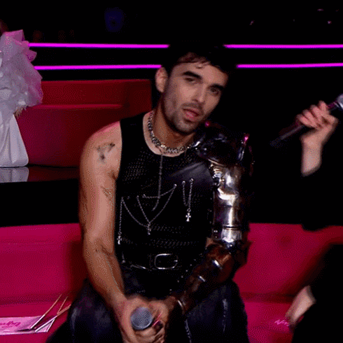 a man is holding a microphone while wearing a black tank top with the letter n on it