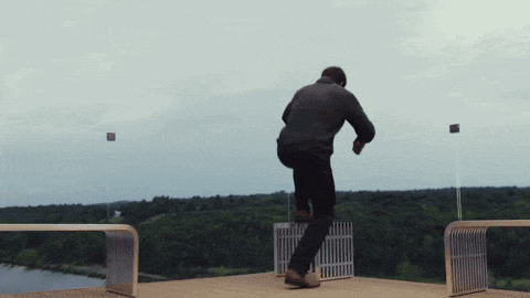 a man stands on a balcony overlooking a river with trees in the background