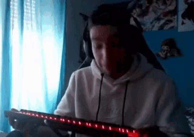 a man wearing headphones is playing a video game on a computer keyboard .