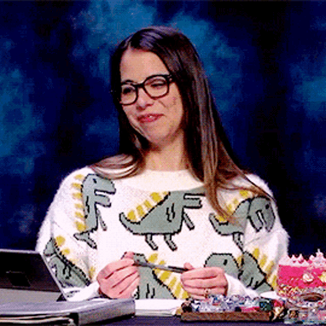 a woman wearing a sweater with dinosaurs on it is holding a lighter