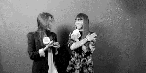two women are hugging each other while holding cups of coffee in a black and white photo .