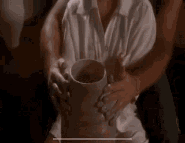 a man is holding a large mug in his hands while sitting on a woman 's lap .