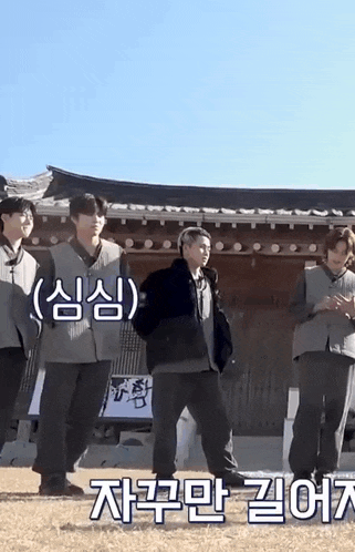 a group of young men are standing in front of a traditional building .