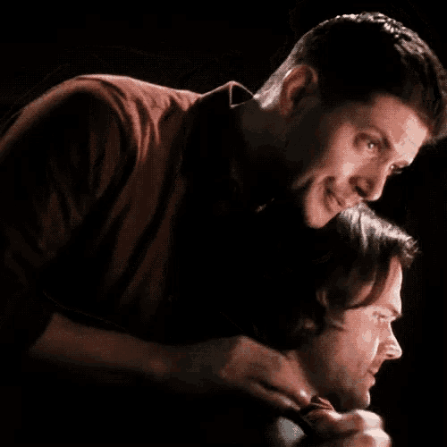 a man in a red shirt is hugging another man in a black shirt