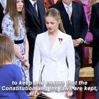 a woman in a white suit is standing in front of a crowd