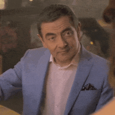 a man in a blue suit and white shirt is talking to a woman in a restaurant .