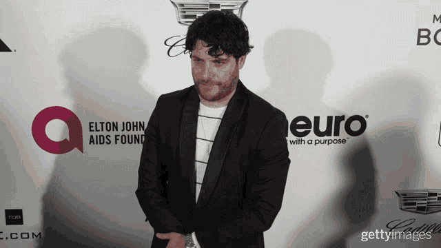 a man in a black suit stands in front of a euro sign