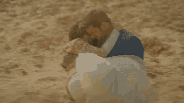 a man is carrying a woman in his arms on a sandy beach