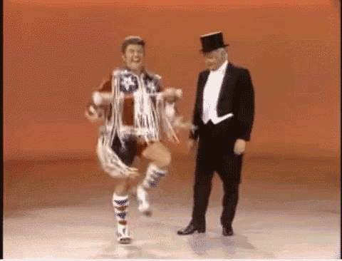 a man in a tuxedo is standing next to a man in a top hat .