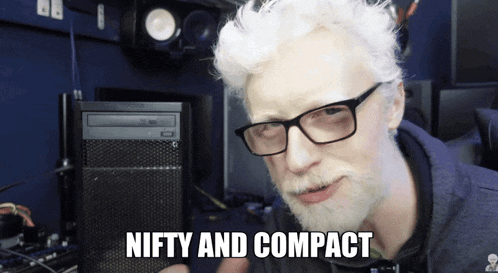 a man with glasses and a beard says " nifty and compact " in front of a computer tower