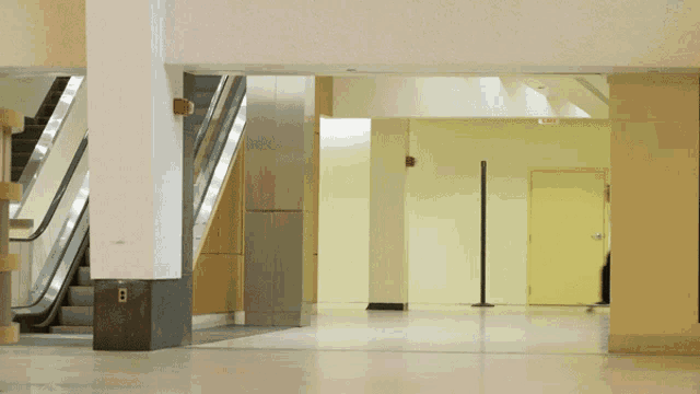 a person walking down an escalator in a hallway with the letter b on the wall