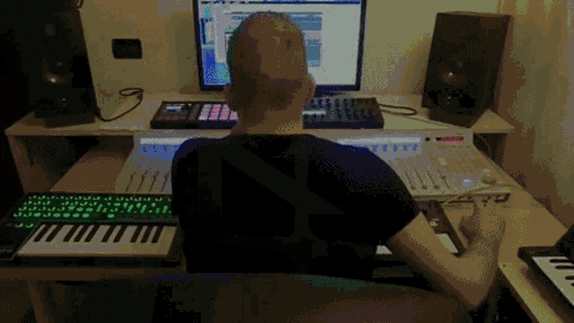a man sits at a desk with a keyboard and a monitor