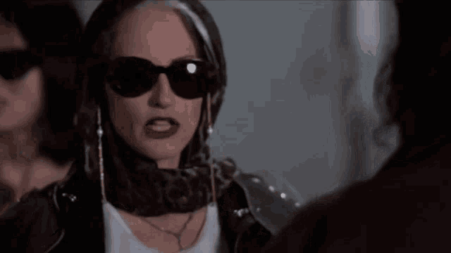 a woman wearing sunglasses is smoking a cigarette and has the word cow on her shirt