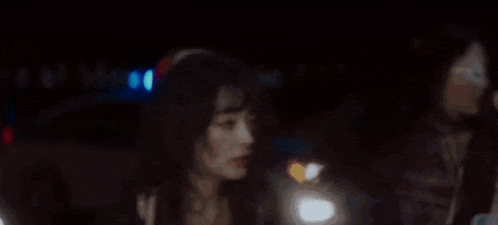 a woman with red hair is sitting in a dark room with a blue light behind her
