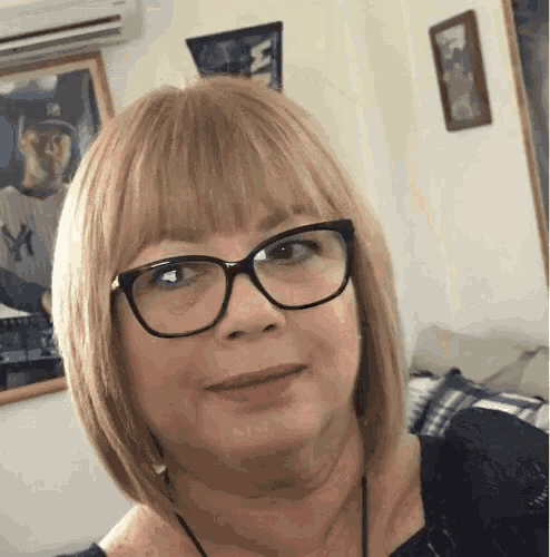 a woman wearing glasses is smiling in front of a picture of a baseball player