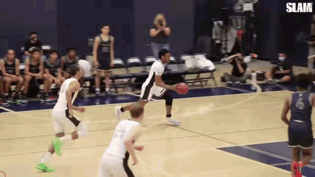 a man is dribbling a basketball on a basketball court while a group of people watch .