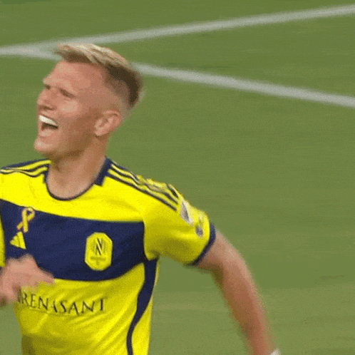 a soccer player wearing a yellow jersey and blue shorts kicks the ball