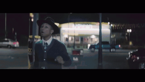 a man in a hat stands in front of a mcdonald 's at night