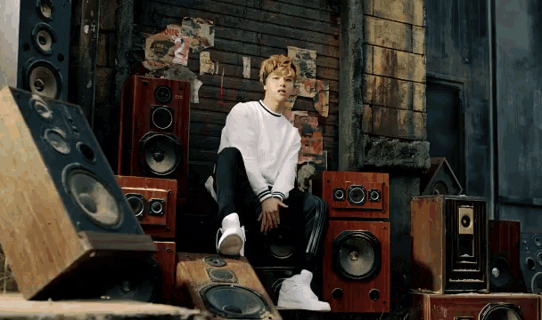 a man is sitting on a pile of speakers with a sticker on the wall that says ' i love you '