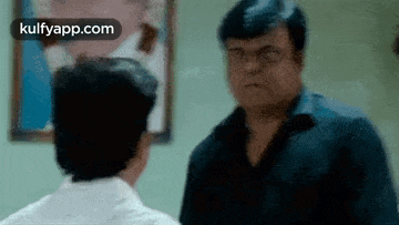 two men are standing next to each other in a room and talking .