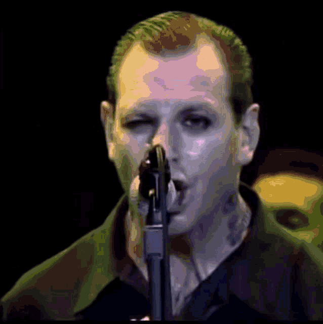a close up of a man singing into a microphone with his eyes closed