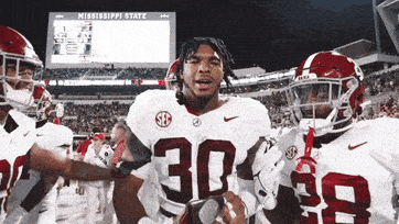 a football player with the number 30 on his jersey stands in front of his teammates