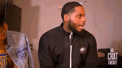 a man wearing a nike jacket is talking to another man