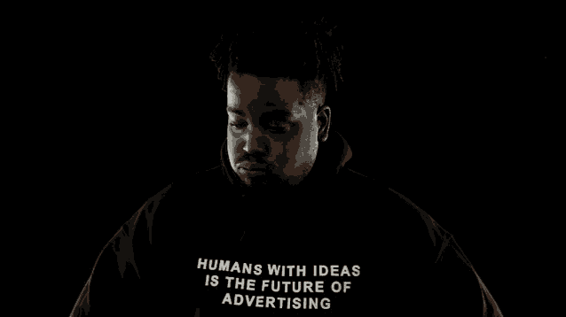a man wearing a black hoodie that says " humans with ideas is the future of advertising "