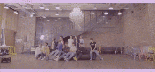 a group of people are dancing in a large room with a chandelier hanging from the ceiling .