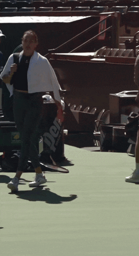a person holding a tennis racquet on a court with a bag that says perf on it
