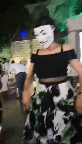 a woman wearing a mask and a floral skirt is dancing