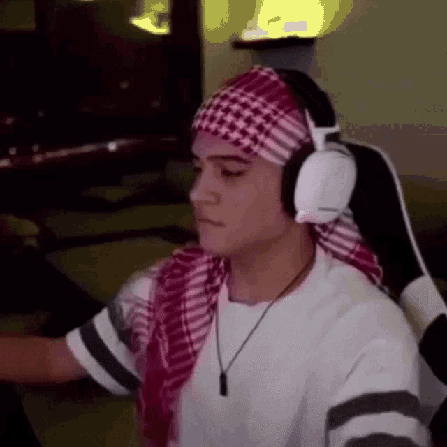 a man wearing headphones and a headband is sitting in a chair .