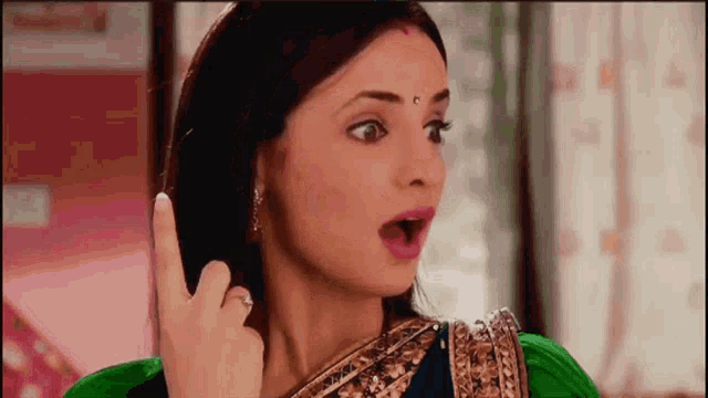 a woman in a green saree is making a funny face