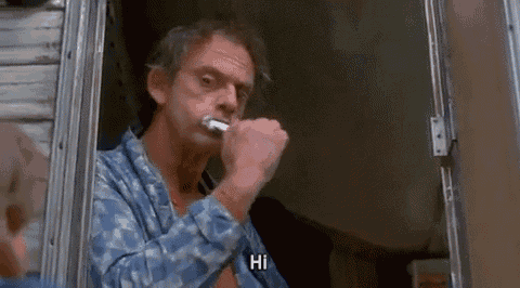 a man is brushing his teeth while looking out of a window and says hi .