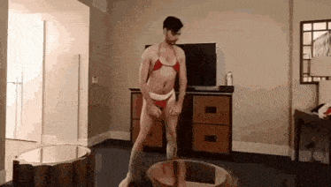 a man in a bikini is standing on a coffee table .