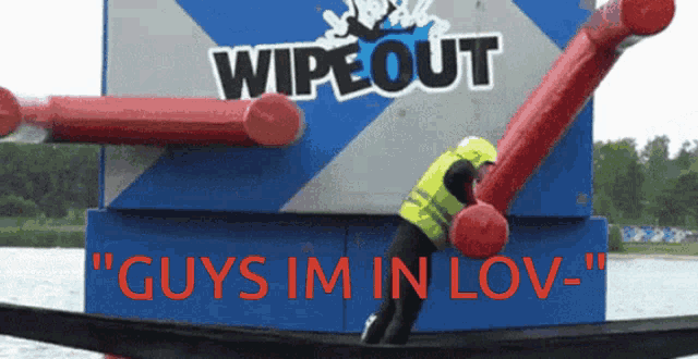 a man in a yellow vest is standing in front of a wipe out sign