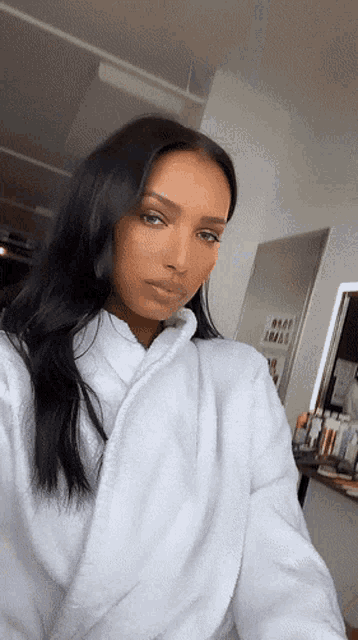 a woman wearing a white robe takes a selfie