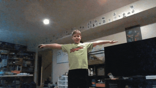 a boy wearing a green shirt that says avengers stands in a living room