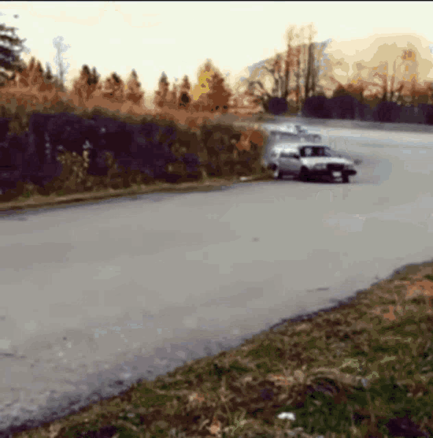 a blurred image of a car driving down a road with trees in the background