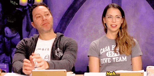 a man and a woman are sitting at a table and the woman is wearing a shirt that says casa pa 1972 dive team